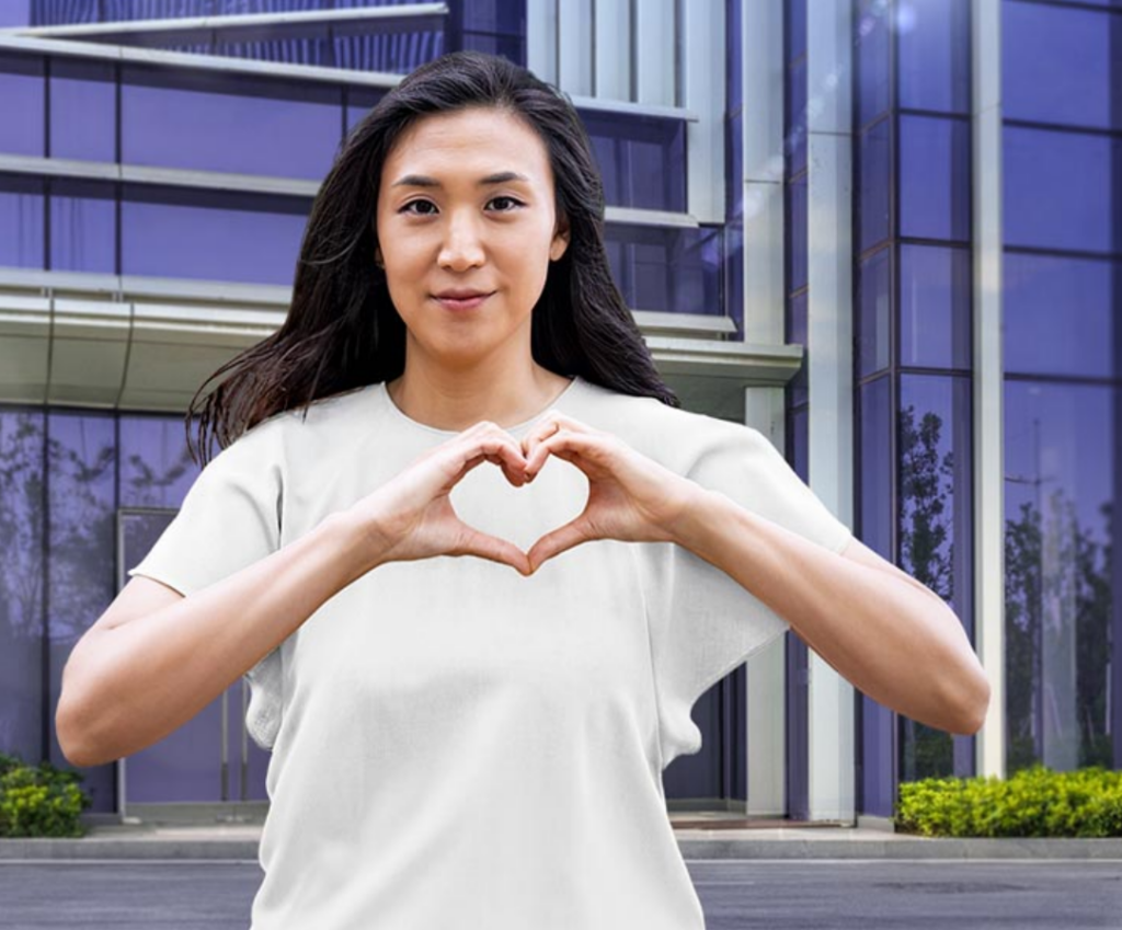 A woman posing with her hands in a heart shape to show Internal Women's Day “Inspiring Inclusion” hand-heart pose