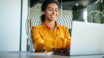 Smiling woman using a laptop, representing a positive experience of an accessible digital report.