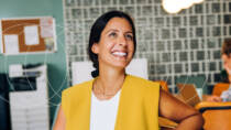 Smiling employee in a relaxed office setting, reflecting positive workplace wellbeing