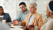 Senior leader speaking with colleagues during a workplace meeting, representing honest leadership communication during organisational change.