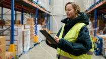 Frontline warehouse employee using a tablet at work, illustrating digital communication in a busy frontline environment.